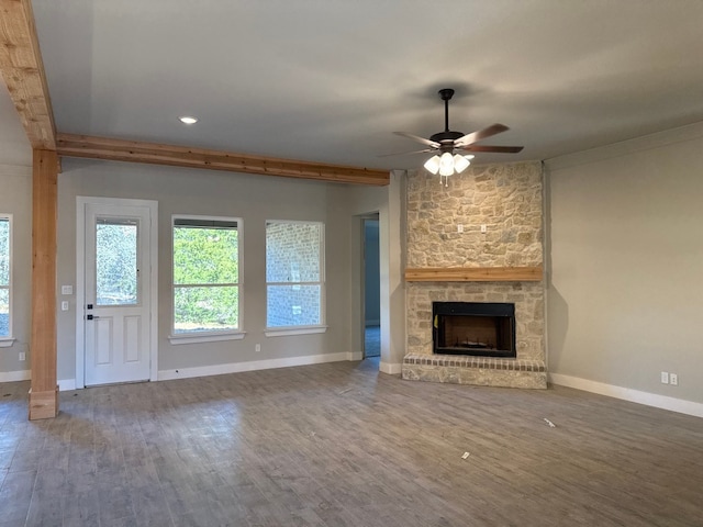 unfurnished living room with hardwood / wood-style floors, a stone fireplace, and ceiling fan