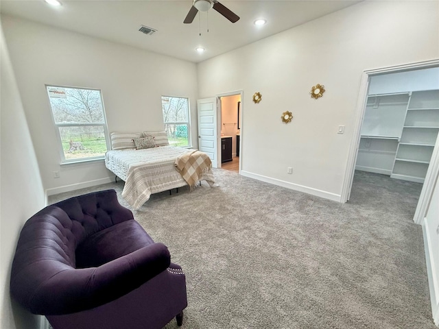 bedroom with light carpet, a closet, ceiling fan, and a spacious closet