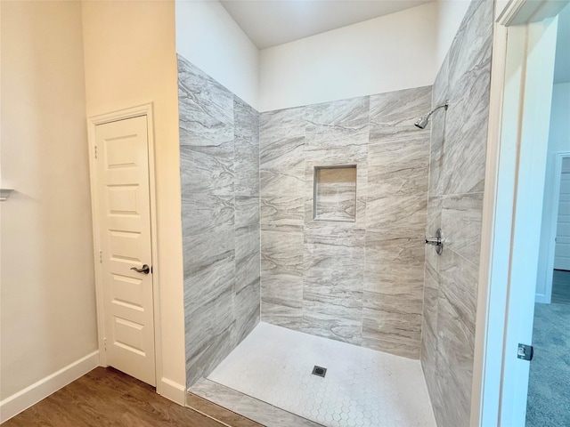 bathroom featuring hardwood / wood-style flooring and a tile shower