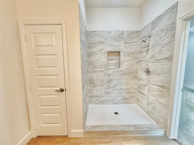 bathroom featuring hardwood / wood-style flooring and a tile shower