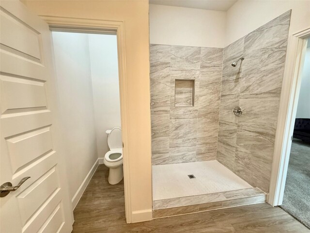 bathroom with tiled shower and wood-type flooring