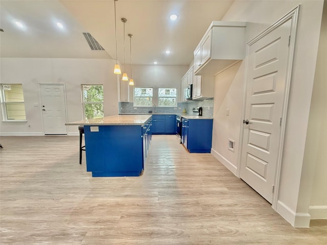 kitchen with a center island, white cabinetry, blue cabinets, decorative light fixtures, and a breakfast bar area