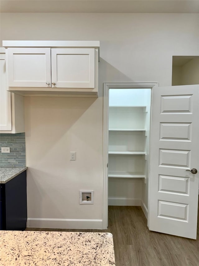 interior space with white cabinets, light stone countertops, dark hardwood / wood-style floors, and tasteful backsplash