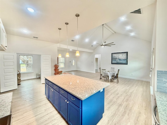 kitchen featuring pendant lighting, high vaulted ceiling, blue cabinets, light stone countertops, and light hardwood / wood-style flooring