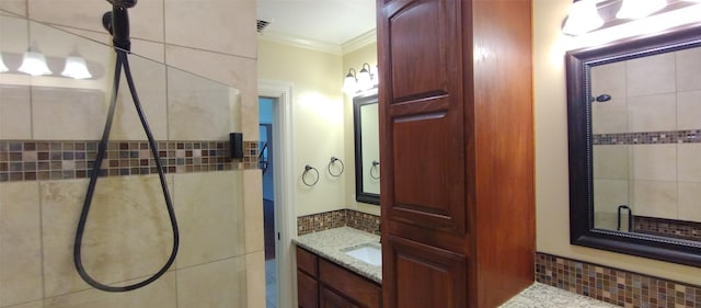 bathroom featuring vanity, tiled shower, and ornamental molding