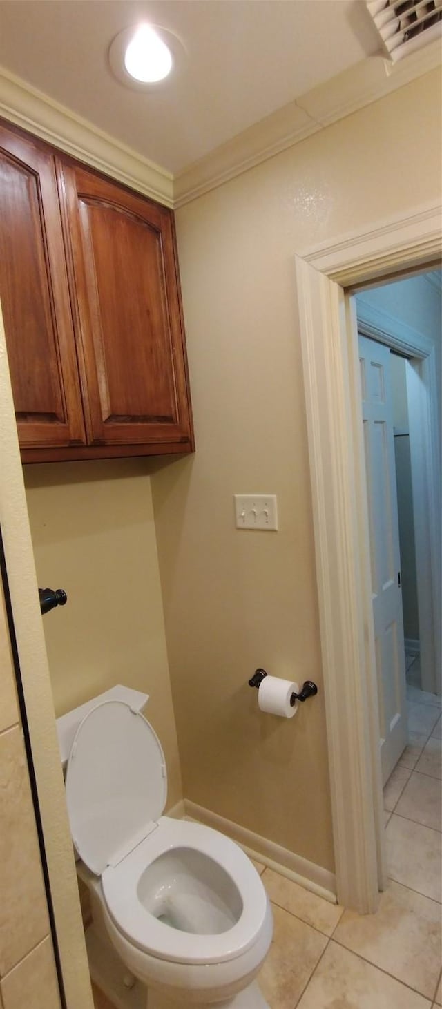 bathroom featuring tile patterned flooring, ornamental molding, and toilet