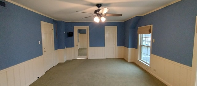 empty room with ornamental molding, ceiling fan, and dark carpet