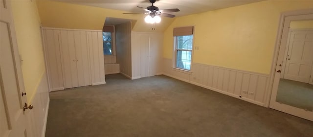 unfurnished bedroom with ceiling fan, lofted ceiling, and dark colored carpet