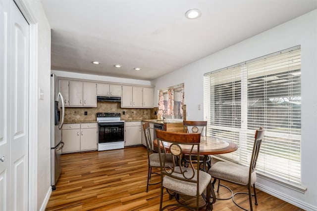 kitchen with tasteful backsplash, plenty of natural light, electric range oven, and hardwood / wood-style floors