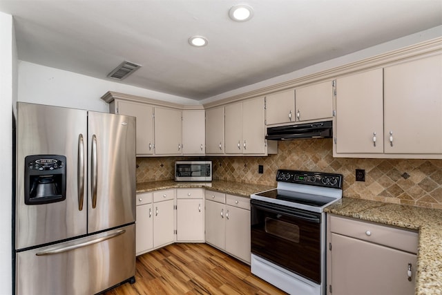 kitchen featuring tasteful backsplash, cream cabinets, light hardwood / wood-style floors, and appliances with stainless steel finishes