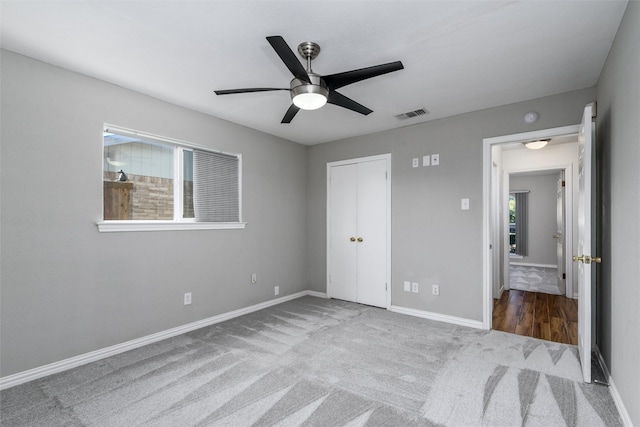 unfurnished bedroom featuring multiple windows, light colored carpet, a closet, and ceiling fan