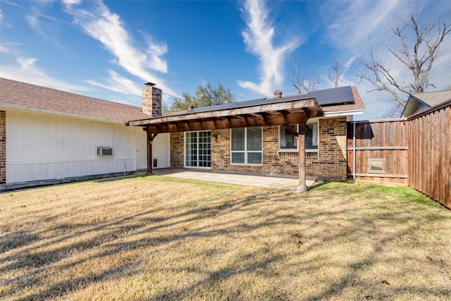 rear view of house featuring a yard, a patio, and solar panels