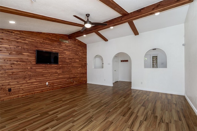 unfurnished living room featuring dark hardwood / wood-style flooring, vaulted ceiling with beams, ceiling fan, and wooden walls