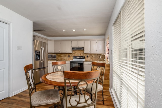 kitchen with dark wood-type flooring, stainless steel refrigerator with ice dispenser, sink, range with electric cooktop, and backsplash