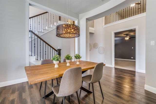 dining room featuring a towering ceiling, dark hardwood / wood-style flooring, and ceiling fan with notable chandelier