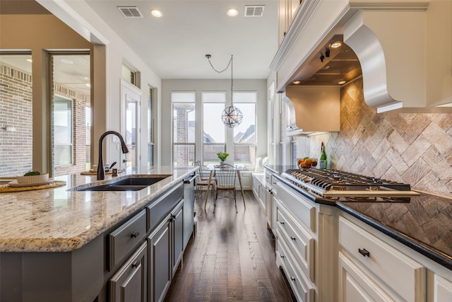 kitchen with sink, decorative light fixtures, dark stone countertops, stainless steel appliances, and white cabinets