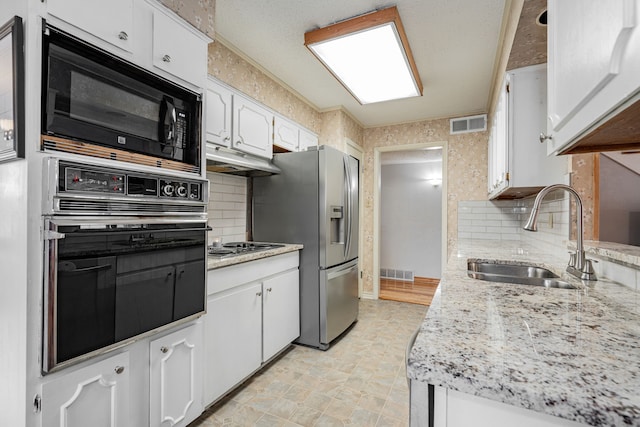 kitchen featuring tasteful backsplash, white cabinetry, sink, and black appliances