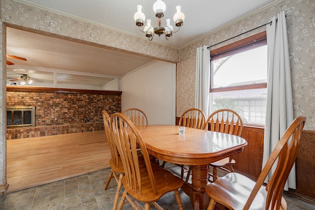 dining space featuring ceiling fan with notable chandelier, a fireplace, and ornamental molding