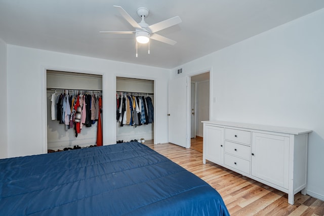 bedroom with ceiling fan, light hardwood / wood-style floors, and multiple closets