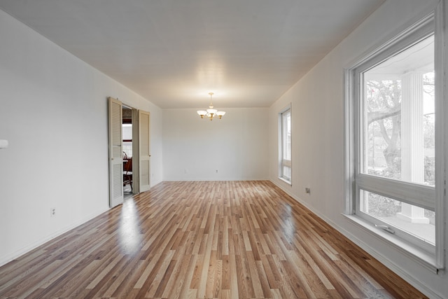 spare room featuring an inviting chandelier and light hardwood / wood-style floors