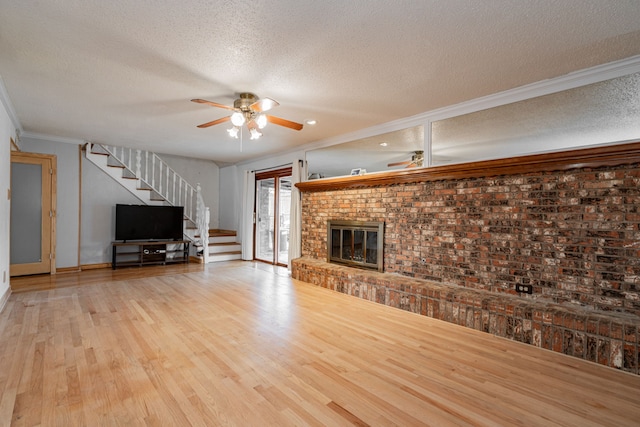 unfurnished living room with a fireplace, ceiling fan, light hardwood / wood-style floors, crown molding, and a textured ceiling