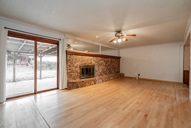 unfurnished living room featuring ceiling fan, ornamental molding, a brick fireplace, and light hardwood / wood-style flooring