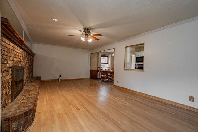 unfurnished living room featuring ornamental molding, a brick fireplace, a textured ceiling, and light hardwood / wood-style floors