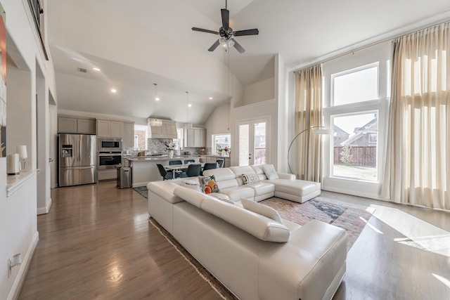 living room with dark wood-type flooring, high vaulted ceiling, french doors, and ceiling fan