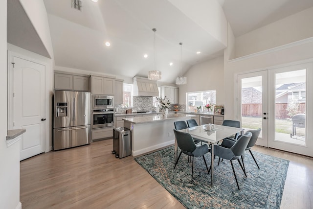 dining area with light hardwood / wood-style flooring, high vaulted ceiling, and french doors