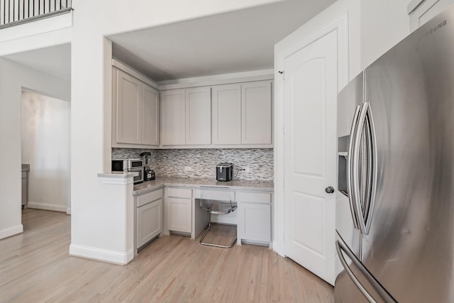 kitchen featuring tasteful backsplash, light wood-type flooring, gray cabinets, and stainless steel refrigerator with ice dispenser