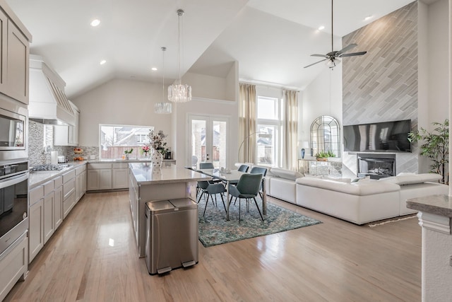 kitchen with custom exhaust hood, appliances with stainless steel finishes, high vaulted ceiling, and decorative light fixtures