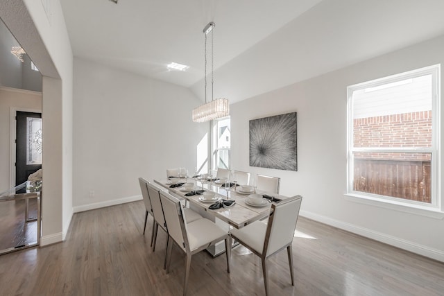 dining area featuring vaulted ceiling, a healthy amount of sunlight, and hardwood / wood-style floors