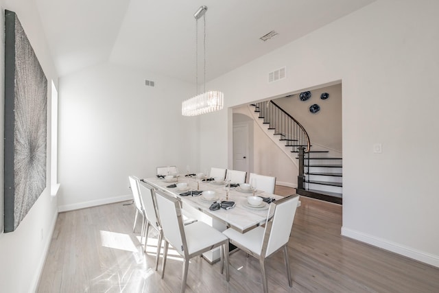 dining space featuring a notable chandelier, vaulted ceiling, and light wood-type flooring