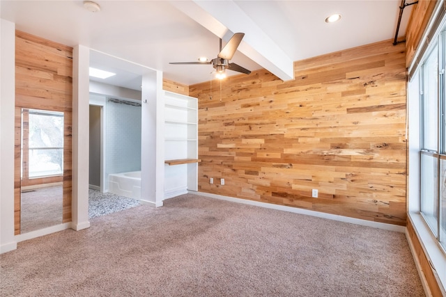 unfurnished bedroom with wooden walls, beamed ceiling, and carpet