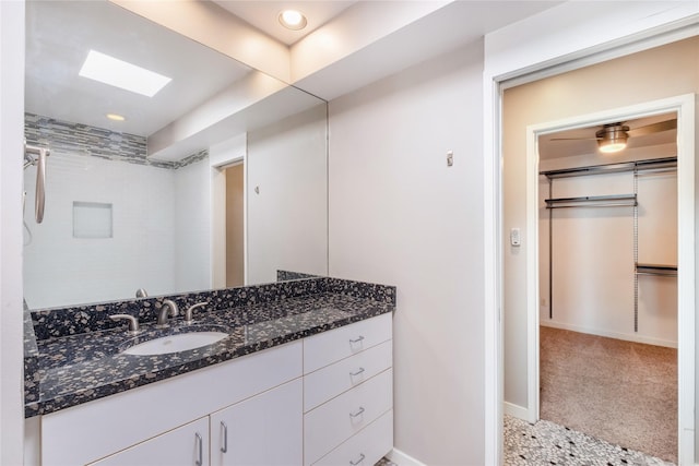 bathroom featuring walk in shower, vanity, and a skylight