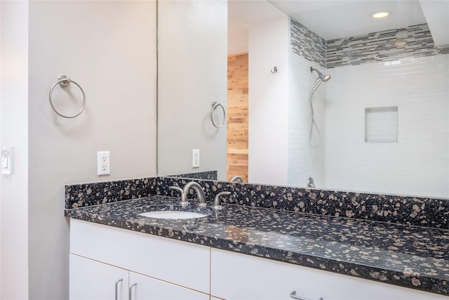 bathroom with tiled shower and vanity