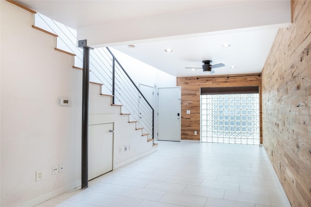 stairs featuring ceiling fan and wood walls