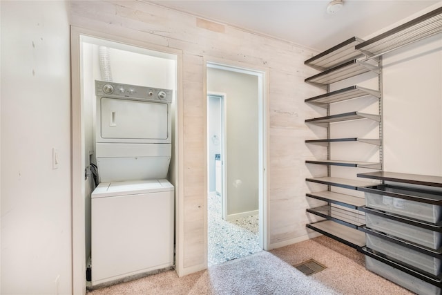 clothes washing area featuring stacked washer / dryer and light colored carpet