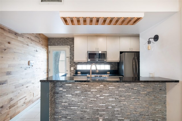 kitchen featuring stainless steel appliances, sink, dark stone counters, and kitchen peninsula