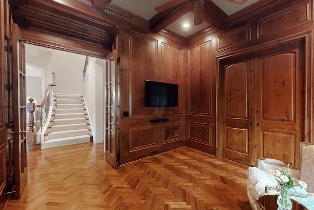 interior space with ceiling fan, beam ceiling, coffered ceiling, ornamental molding, and light parquet flooring