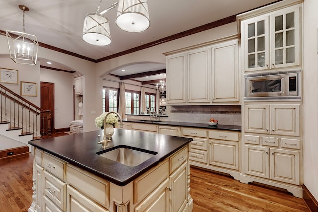 kitchen featuring pendant lighting, sink, stainless steel microwave, and cream cabinets