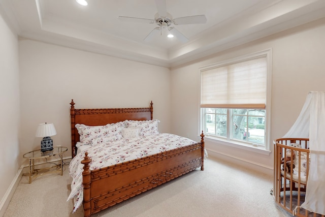 carpeted bedroom with ceiling fan and a raised ceiling