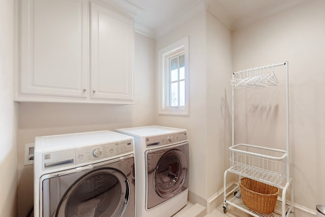 clothes washing area featuring cabinets, ornamental molding, and washer and clothes dryer