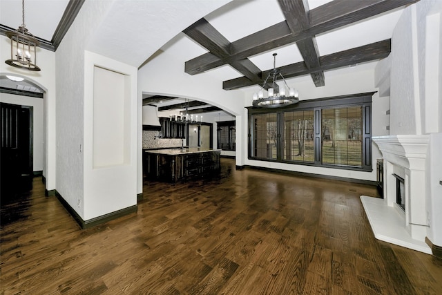 unfurnished living room with dark wood-type flooring, coffered ceiling, a chandelier, and beamed ceiling