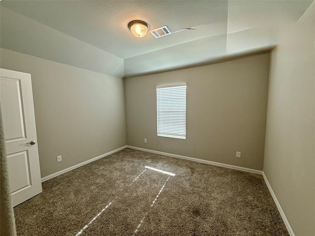 spare room featuring lofted ceiling and dark carpet