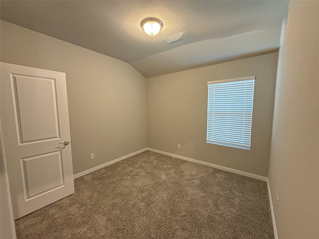 empty room featuring lofted ceiling, a textured ceiling, and carpet flooring