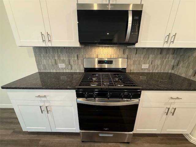 kitchen featuring stainless steel appliances, white cabinetry, backsplash, and dark stone counters