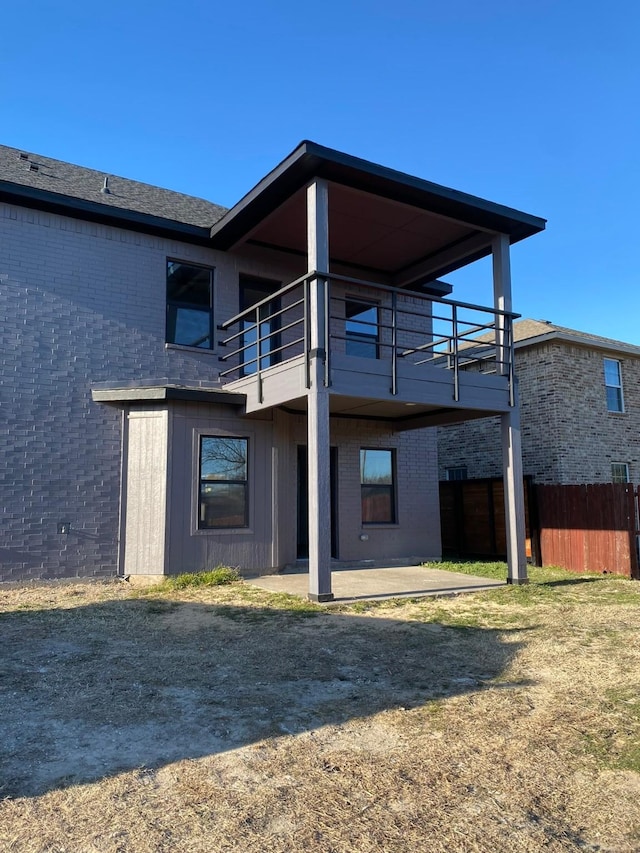 back of house featuring a lawn, a patio, and a balcony