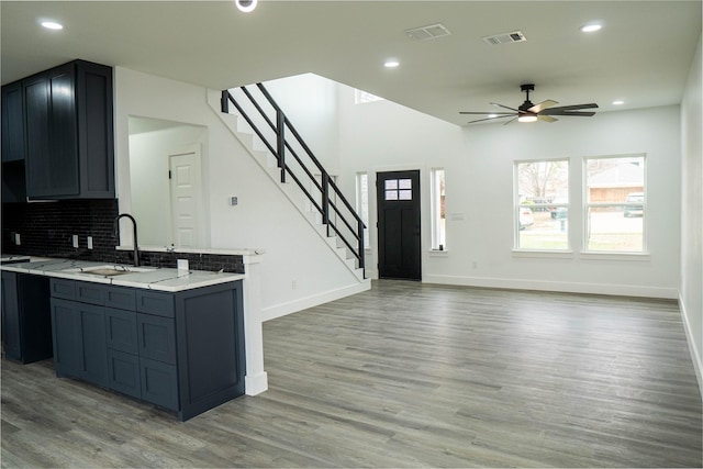 kitchen with tasteful backsplash, ceiling fan, light stone countertops, and light hardwood / wood-style floors