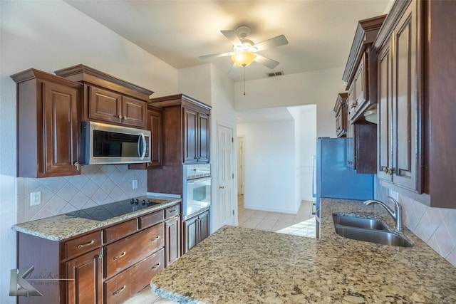 kitchen with sink, ceiling fan, white oven, black electric cooktop, and decorative backsplash